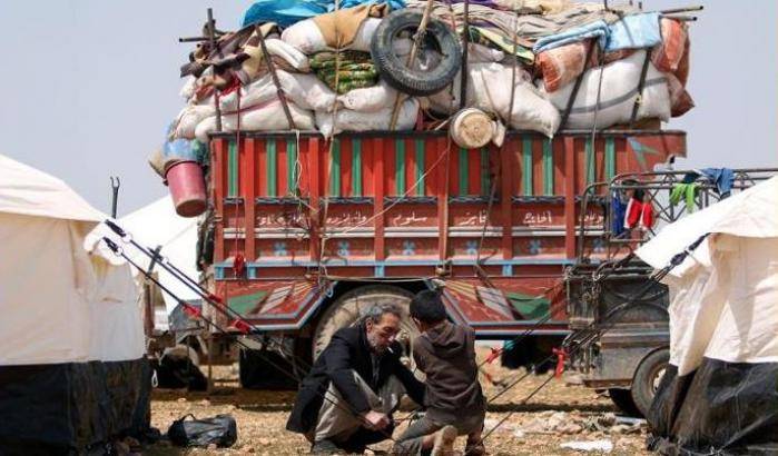 Un uomo e un bambino montano una tenda in un campo a Manbij.  Foto: Reuters