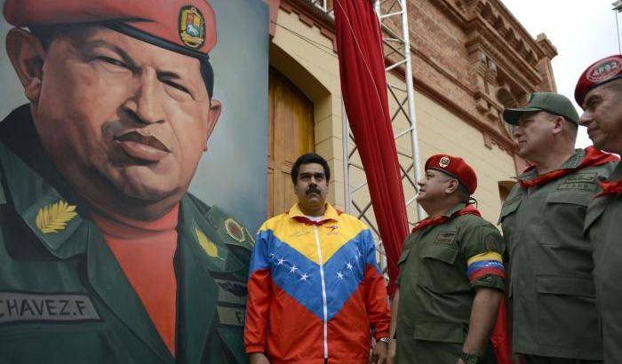 Il presidente Maduro in piedi di fronte a un ritratto del predecessore Chavez
