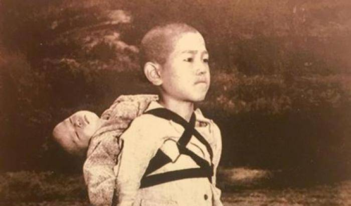 Un ragazzo con in spalla il fratellino morto nel bombardamento atomico