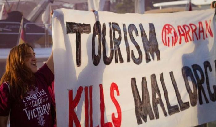 Un'attivista di Arran con un cartello "Il turismo uccide Maiorca"
