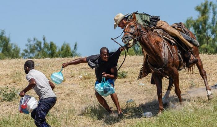 Poliziotti a cavallo frustano migranti